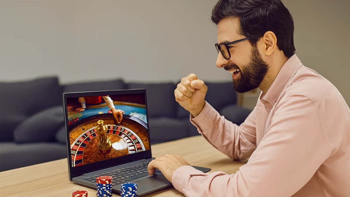 Man excitedly playing online roulette at home on his laptop