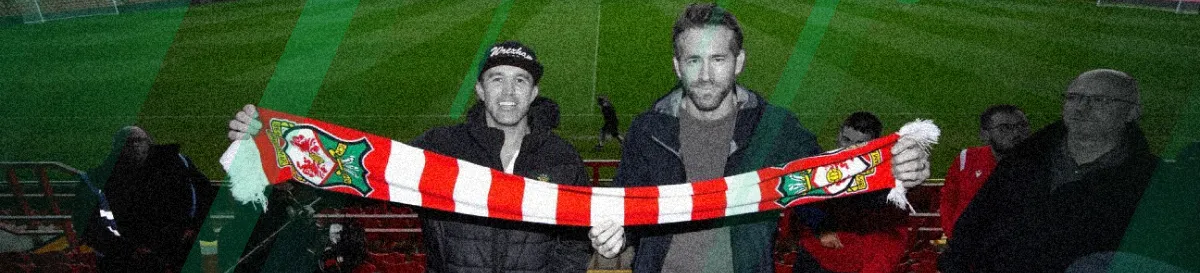 Ryan Reynolds and Rob McElhenney holding Wrexham AFC scarf at a football stadium